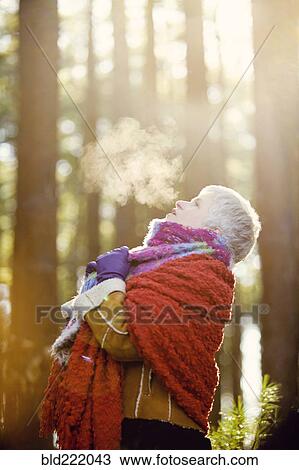 Stock Image - Older Caucasian woman breathing steam outdoors. Fotosearch
