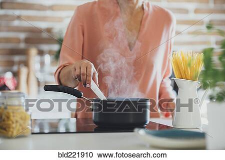 Stock Image - Older Caucasian woman cooking in kitchen. Fotosearch