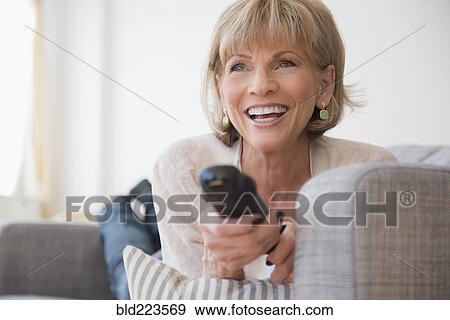 Stock Photo - Older Caucasian woman laying on sofa watching television. Fotosearch