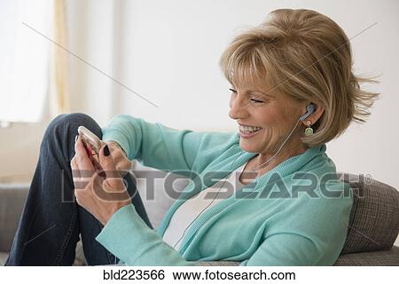 Stock Photograph - Older Caucasian woman listening to music on cell phone. Fotosearch