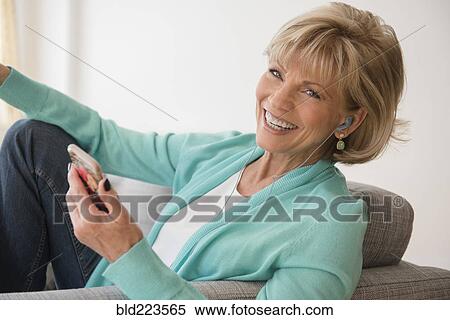 Stock Photography - Older Caucasian woman listening to music on cell phone. Fotosearch