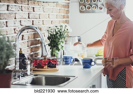 Stock Image - Older Caucasian woman making coffee in kitchen. Fotosearch
