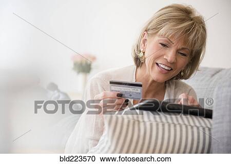 Stock Image - Older Caucasian woman online shopping with digital tablet. Fotosearch