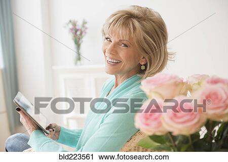Stock Image - Older Caucasian woman reading digital tablet. Fotosearch