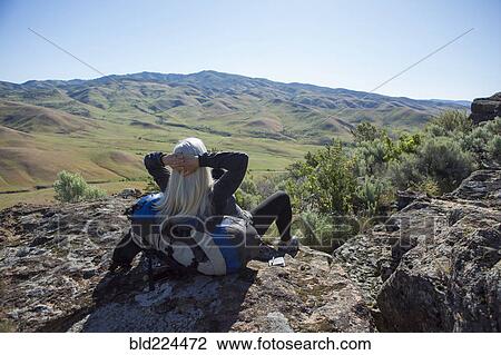 Older Caucasian woman sitting on rocks leaning on backpack View Large Photo Image Stock Image - Older Caucasian woman sitting on rocks leaning on backpack. Fotosearch