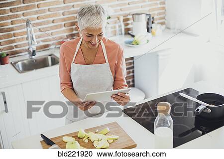 Older Caucasian woman using digital tablet in kitchen View Large Photo Image Stock Image - Older Caucasian woman using digital tablet in kitchen. Fotosearch