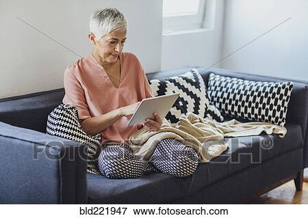 Older Caucasian woman using digital tablet on sofa View Large Photo Image Stock Photo - Older Caucasian woman using digital tablet on sofa. Fotosearch