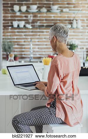 Older Caucasian woman using laptop in kitchen View Large Photo Image Stock Photo - Older Caucasian woman using laptop in kitchen. Fotosearch
