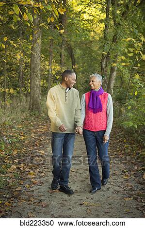 Older couple holding hands walking in forest View Large Photo Image Stock Image - Older couple holding hands walking in forest. Fotosearch