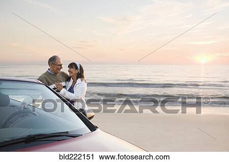 Older couple standing at car on beach View Large Photo Image Stock Image - Older couple standing at car on beach. Fotosearch