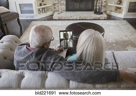 Stock Image - Older couple video chatting with digital tablet. Fotosearch