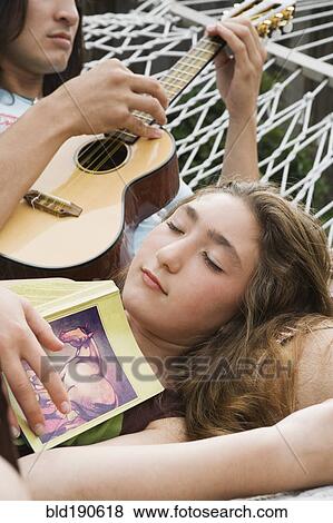 Stock Photo - Pacific Islander man playing ukulele for sister. Fotosearch