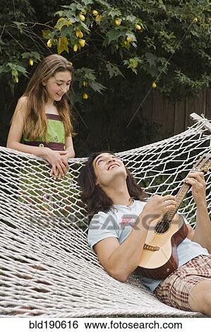 Stock Photograph - Pacific Islander man playing ukulele for sister. Fotosearch