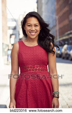 Stock Photograph - Pacific Islander woman smiling on city sidewalk. Fotosearch
