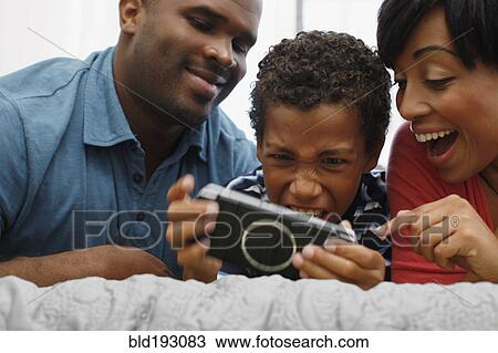 Parents watching son play video game View Large Photo Image Stock Image - Parents watching son play video game. Fotosearch