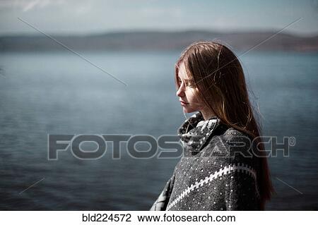 Stock Image - Pensive Caucasian girl at lake. Fotosearch