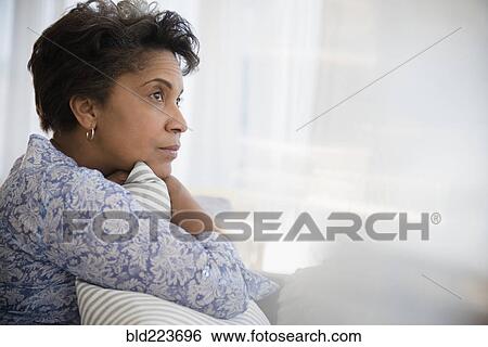 Stock Photograph - Pensive older Black woman clutching pillow. Fotosearch