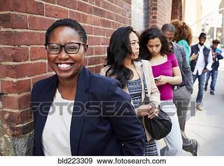 Stock Photo - People waiting in line on sidewalk. Fotosearch
