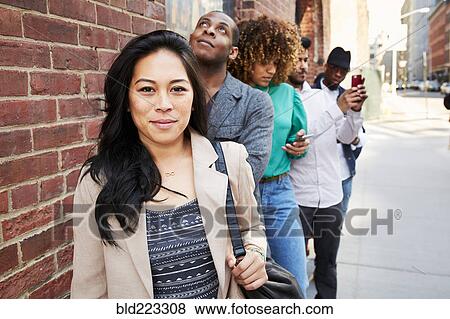 People waiting in line on sidewalk with cell phones View Large Photo Image Stock Photo - People waiting in line on sidewalk with cell phones. Fotosearch