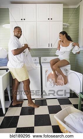 Stock Photography - Playful couple folding laundry. Fotosearch