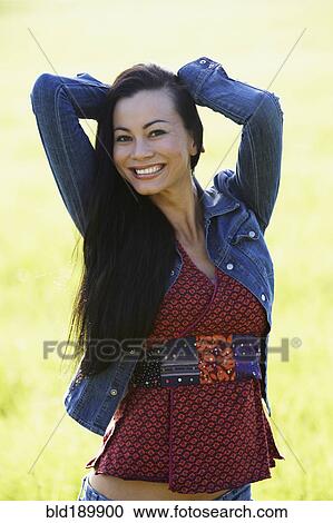 Stock Image - Portrait of Asian woman hands behind head. Fotosearch