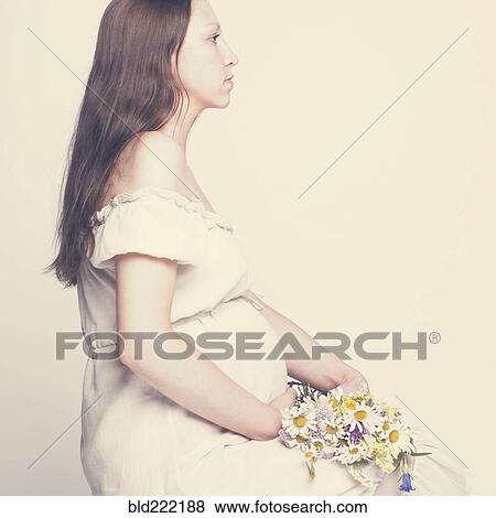 Stock Photo - Pregnant Caucasian woman holding bouquet of flowers. Fotosearch