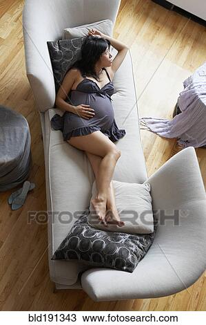 Stock Image - Pregnant mixed race woman relaxing in living room. Fotosearch