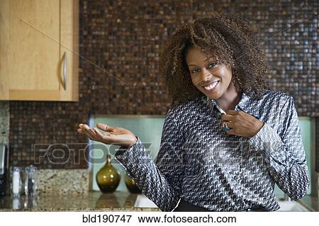 Proud African woman showing off modern kitchen View Large Photo Image Stock Photo - Proud African woman showing off modern kitchen. Fotosearch