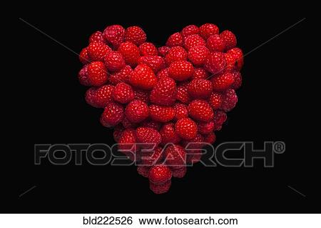 Stock Photograph - Raspberries in shape of heart on black background. Fotosearch