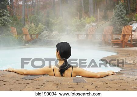 Picture - Rear view of woman sitting in hot tub. Fotosearch