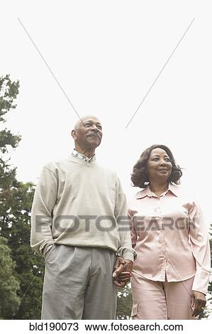 Stock Image - Senior African couple holding hands outdoors. Fotosearch