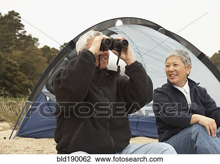 Stock Image - Senior Asian couple camping with binoculars. Fotosearch