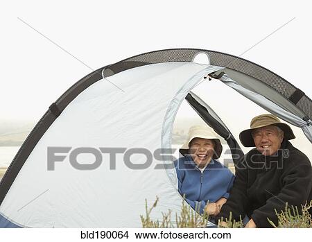 Picture - Senior Asian couple sitting in tent smiling. Fotosearch