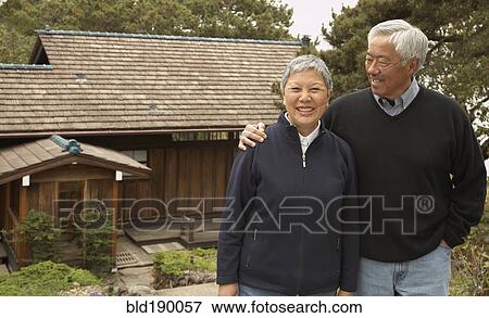 Stock Photo - Senior Asian couple smiling and hugging outdoors. Fotosearch