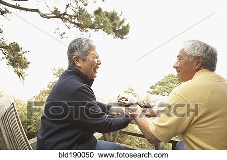 Stock Image - Senior Asian couple talking and laughing outdoors. Fotosearch