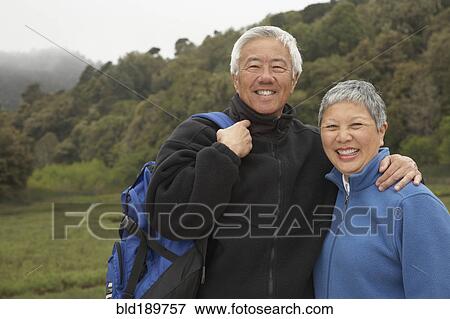 Stock Photo - Senior Asian couple with backpack outdoors. Fotosearch