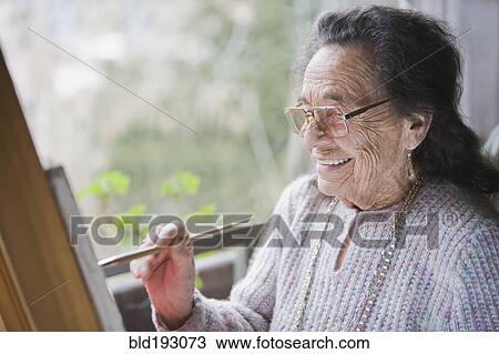 Stock Image - Senior Hispanic woman painting. Fotosearch