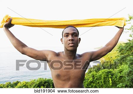 Serious African man holding towel overhead View Large Photo Image Picture - Serious African man holding towel overhead. Fotosearch