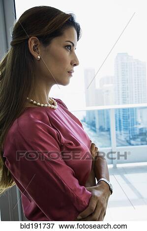 Serious Hispanic woman standing by window with arms crossed View Large Photo Image Stock Photo - Serious Hispanic woman standing by window with arms crossed. Fotosearch