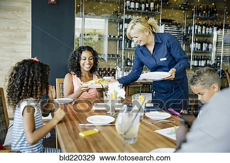 Server bringing food for family in restaurant View Large Photo Image Stock Photo - Server bringing food for family in restaurant. Fotosearch