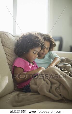 Sisters using digital tablet on sofa View Large Photo Image Stock Image - Sisters using digital tablet on sofa. Fotosearch