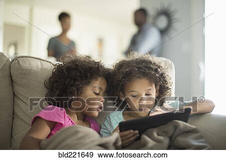 Sisters using digital tablet on sofa View Large Photo Image Stock Photo - Sisters using digital tablet on sofa. Fotosearch