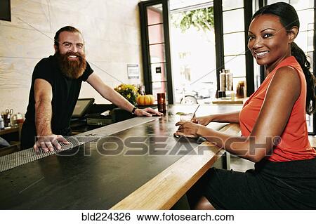 Stock Photograph - Smiling bartender and customer at bar. Fotosearch