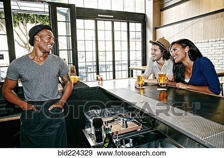 Stock Photo - Smiling bartender and customers at bar. Fotosearch
