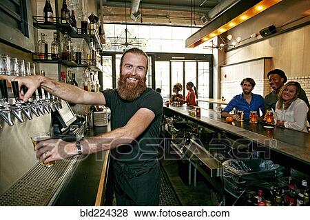 Smiling bartender pouring beer at bar View Large Photo Image Stock Photo - Smiling bartender pouring beer at bar. Fotosearch