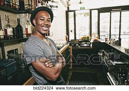 Smiling Black bartender relaxing behind bar View Large Photo Image Picture - Smiling Black bartender relaxing behind bar. Fotosearch