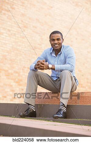 Stock Photo - Smiling black man sitting on staircase. Fotosearch