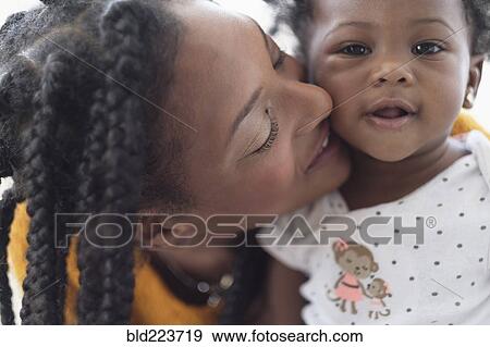 Stock Photo - Smiling Black woman cheek to cheek with baby daughter. Fotosearch