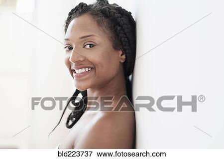 Stock Photo - Smiling Black woman leaning on wall. Fotosearch