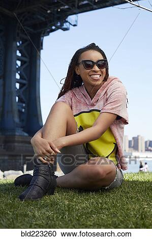 Smiling Black woman sitting in grass at waterfront View Large Photo Image Stock Image - Smiling Black woman sitting in grass at waterfront. Fotosearch